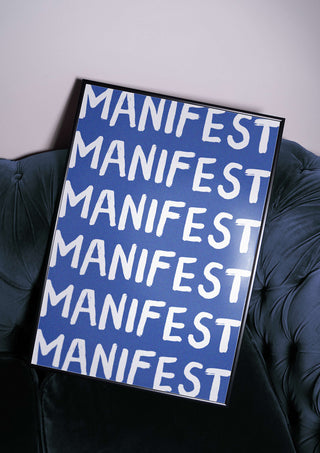Manifest Print. Manifest poster. Blue manifestation art print on velvet sofa. Spiritual poster. Positive print sits framed on top of chesterfield sofa.