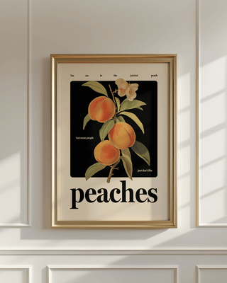 Positive peaches art print in gold frame on white panelled wall.