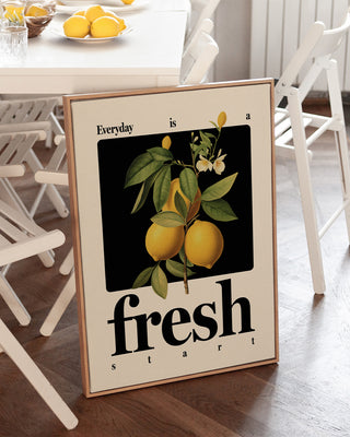 "Everyday is a fresh start" positive quote print in natural wooden frame in kitchen with bowls of lemons. The print features a vintage-inspired lemon illustration and classic bold fonts.