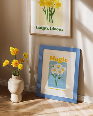 Magic Surrounds You Everyday art print. Hand-drawn watercolour daisies with uplifting butter yellow lettering that reminds you magic is all around. Art print in blue frame with yellow flowers, glassette