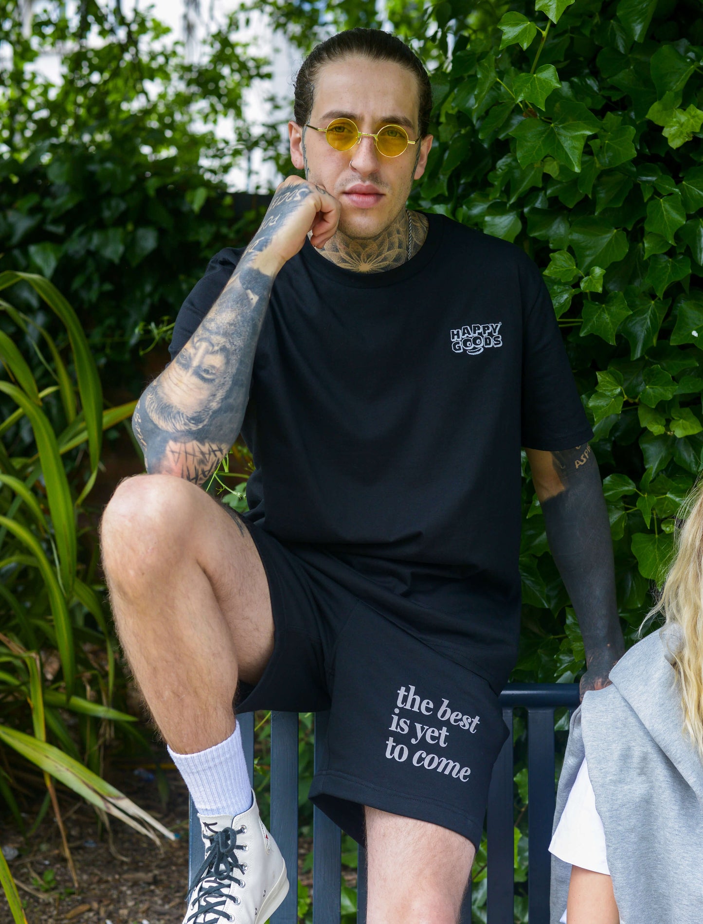 The best is yet to come shorts. positive messaging mental health shorts. Male model wearing black and grey positive affirmation shorts sits on bench in park