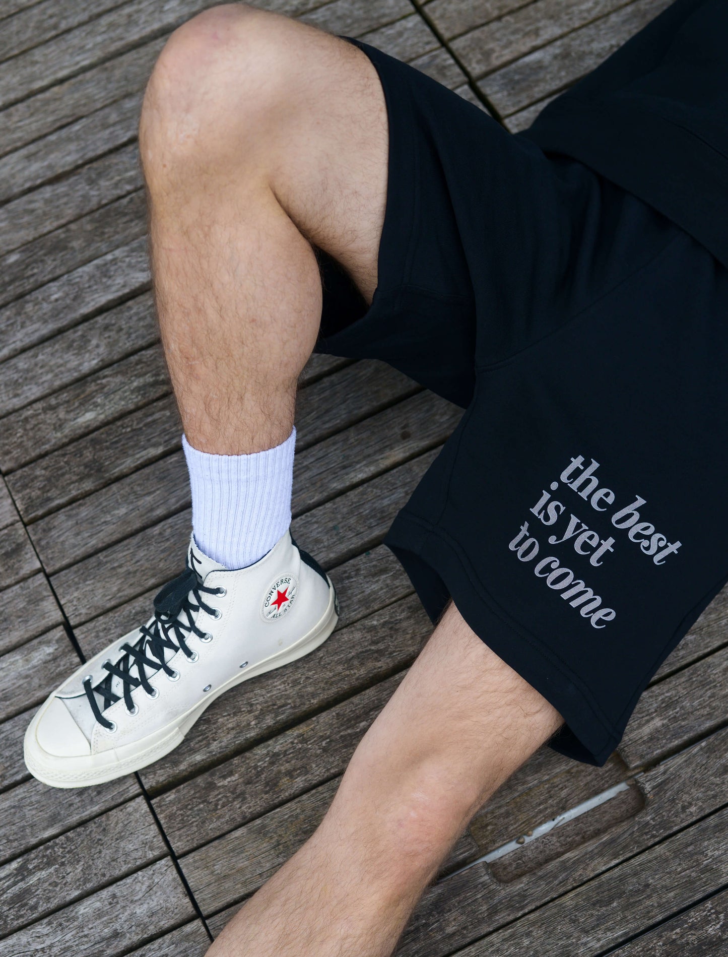 The best is yet to come shorts. positive messaging mental health shorts. Male model lying down wearing positive affirmation shorts