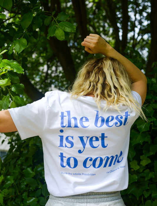 The best is yet to come t-shirt. positive messaging mental health tee. woman wearing tshirt in white and blue in nature