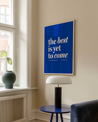 The Best Is Yet To Come blue print in natural wooden frame. Hanging on cream wall above coffee table and lamp