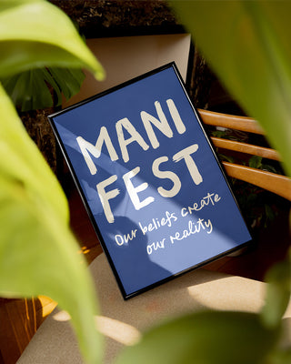 Manifest Print. Manifest poster. Blue manifestation art print in nature. Spiritual poster. Positive print. Framed print sits on outdoor furniture surrounded by tropical plants