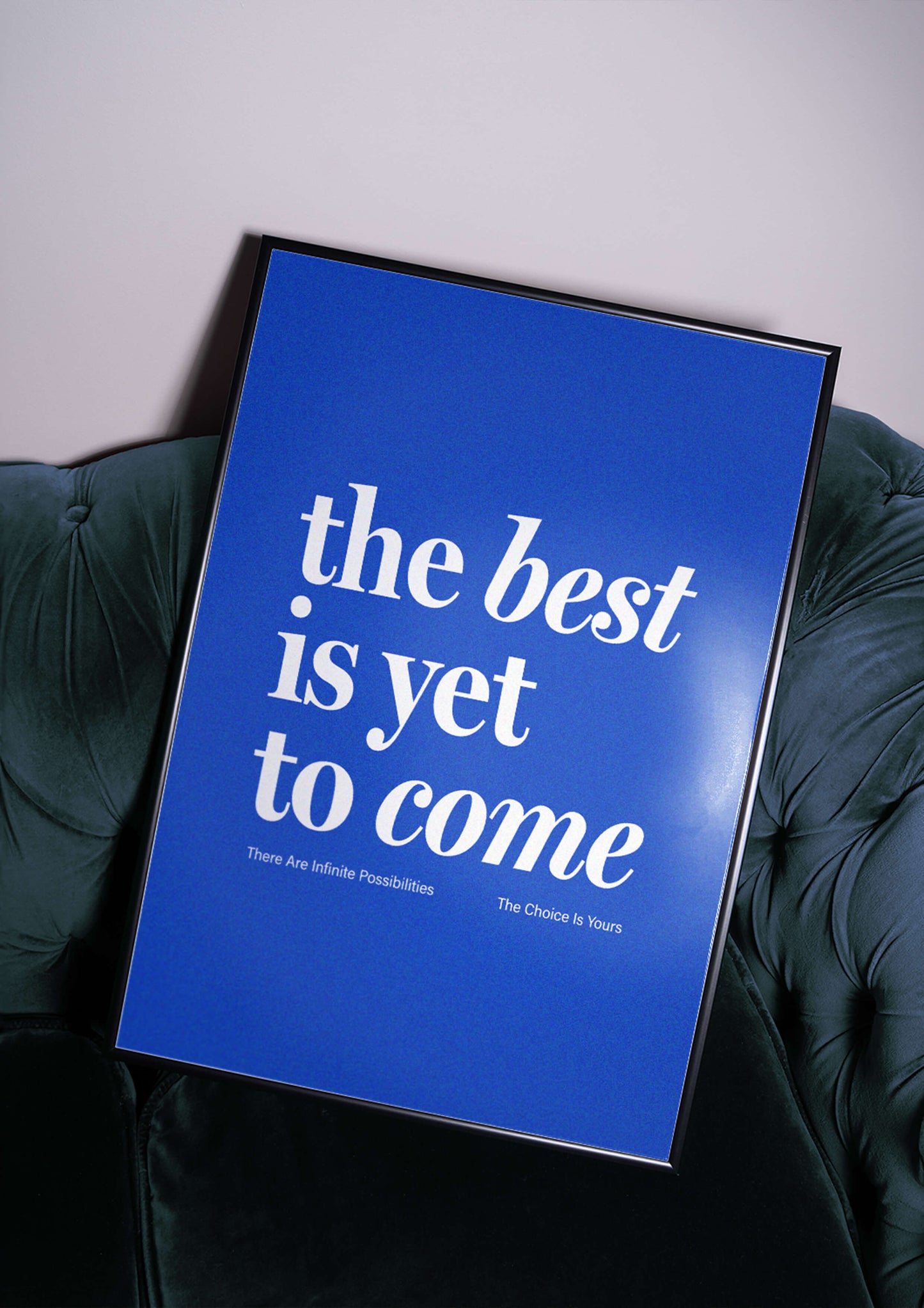 The Best Is Yet To Come blue print in black frame sitting on blue velvet sofa