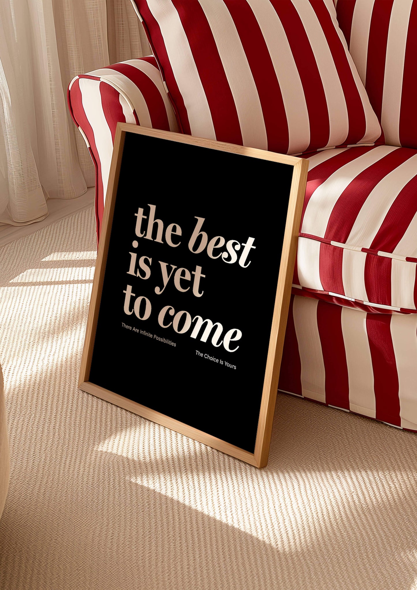 Print reading "the best is yet to come" in black. affirmation print manifestation print mental health prints positive quote print. Framed print in living room leaning against red stripey sofa  