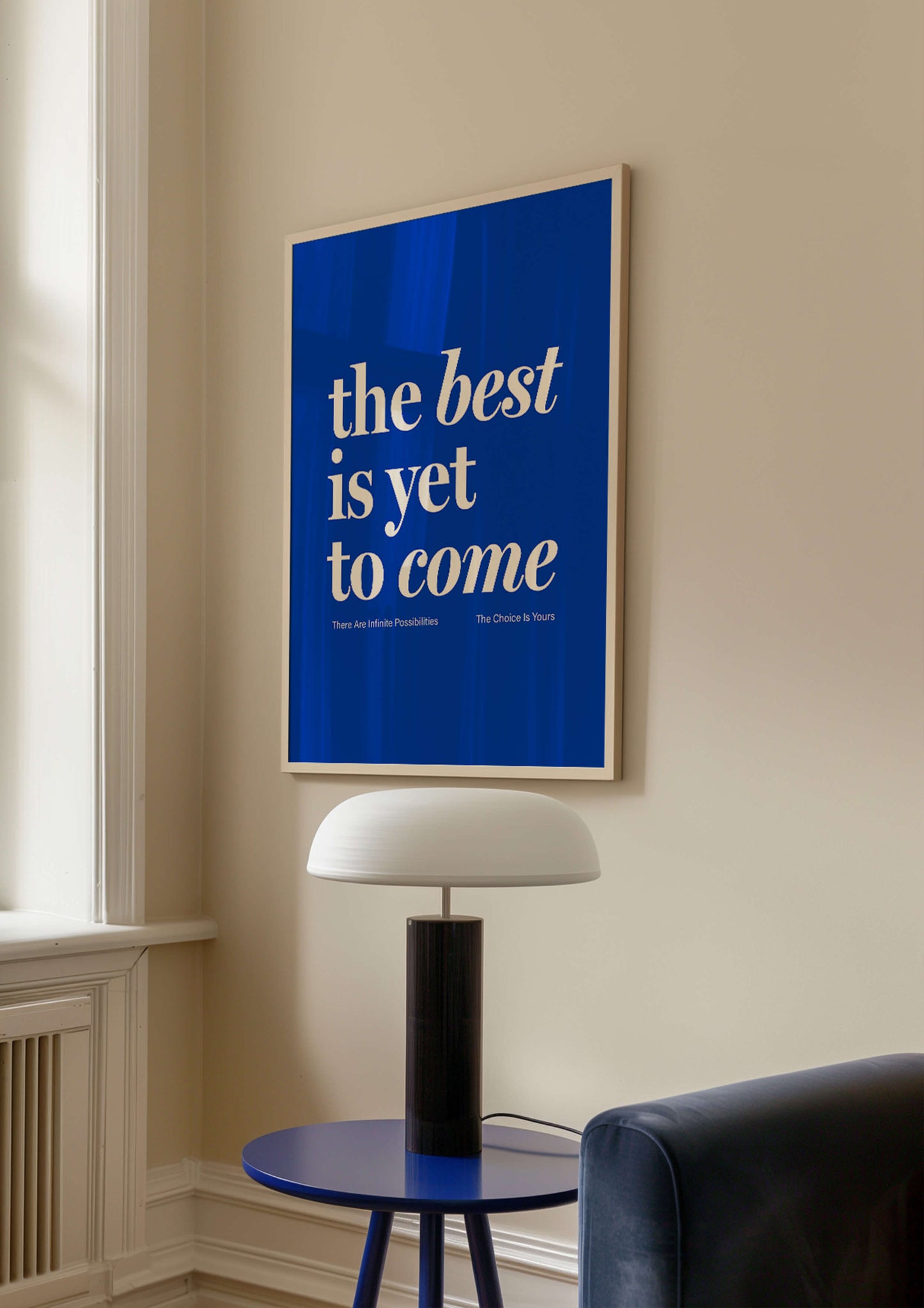 The Best Is Yet To Come blue print in natural wooden frame. Hanging on cream wall above coffee table and lamp