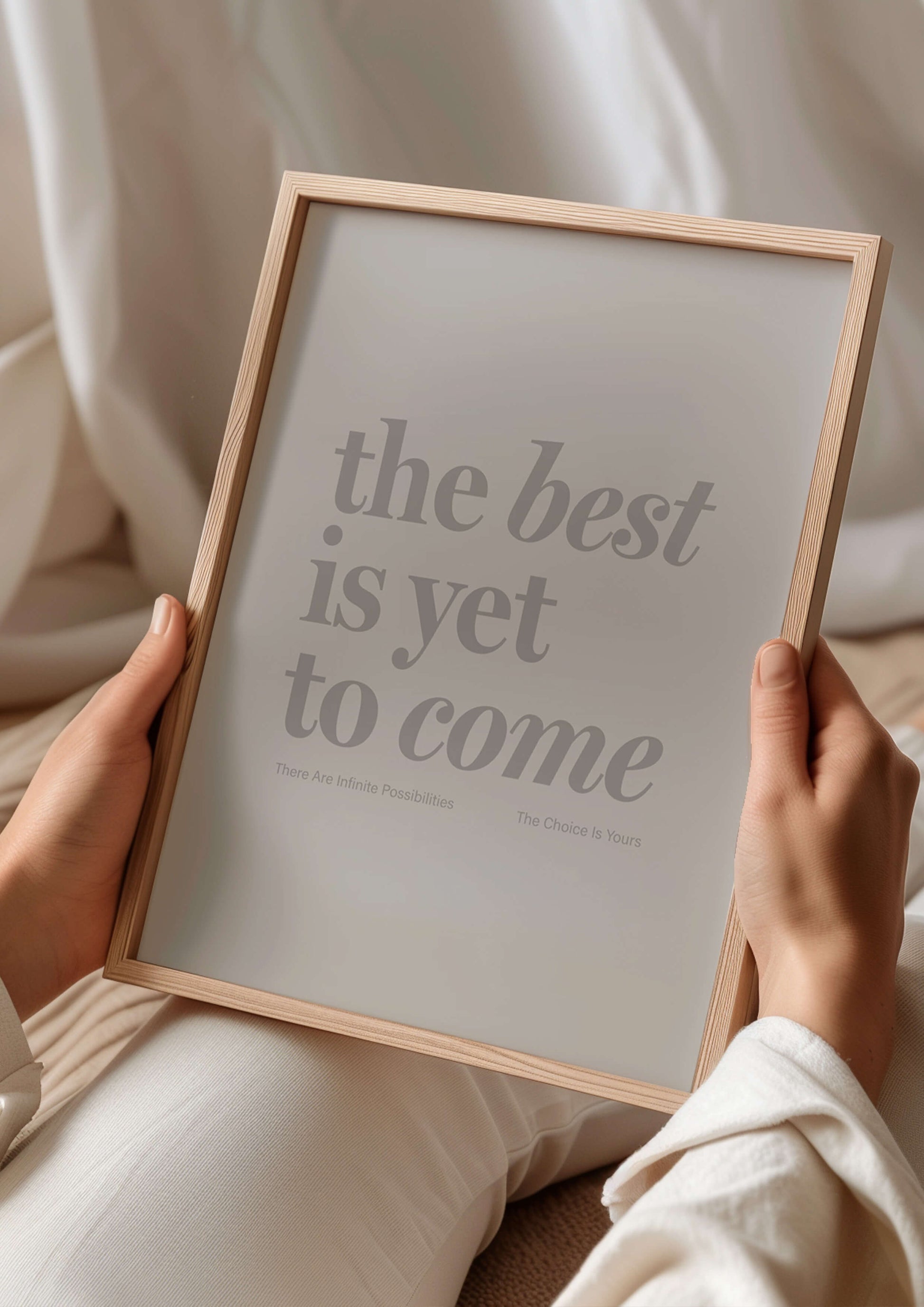 The Best Is Yet To Come print in natural wooden frame. Womans hands hold the print while she lays down