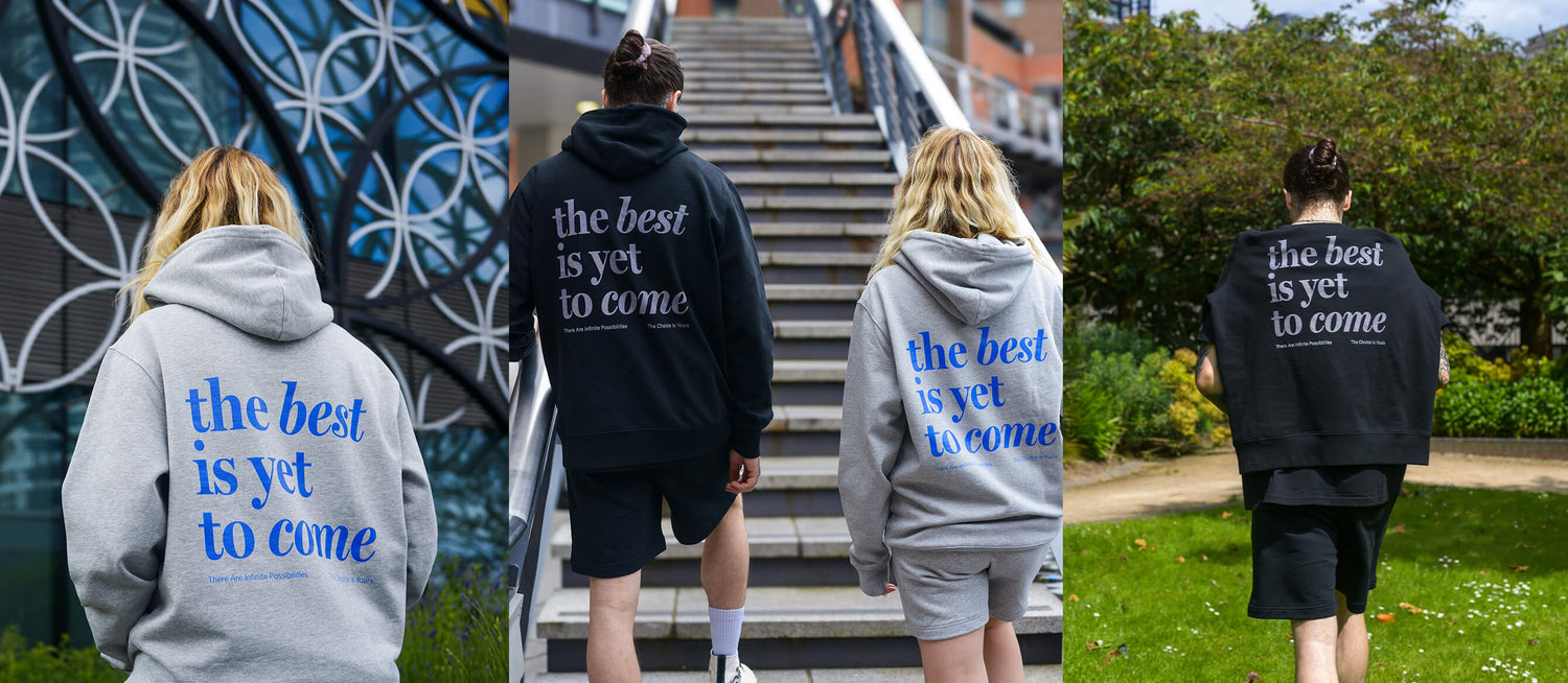 Male and female models wearing The Best Is Yet To Come black and grey essential hoodies