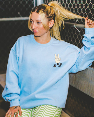 Model wearing oversized main character energy sweater in blue sitting on bench