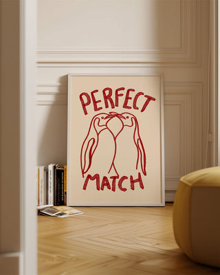 A premium art prints that reads perfect match and features a illustration of two penguins. The wall art decor is framed and hand-drawn in watercolour brushes. Unique gift for valentines day, anniversaries or a loved one. The art print is in red and cream in a modern living room