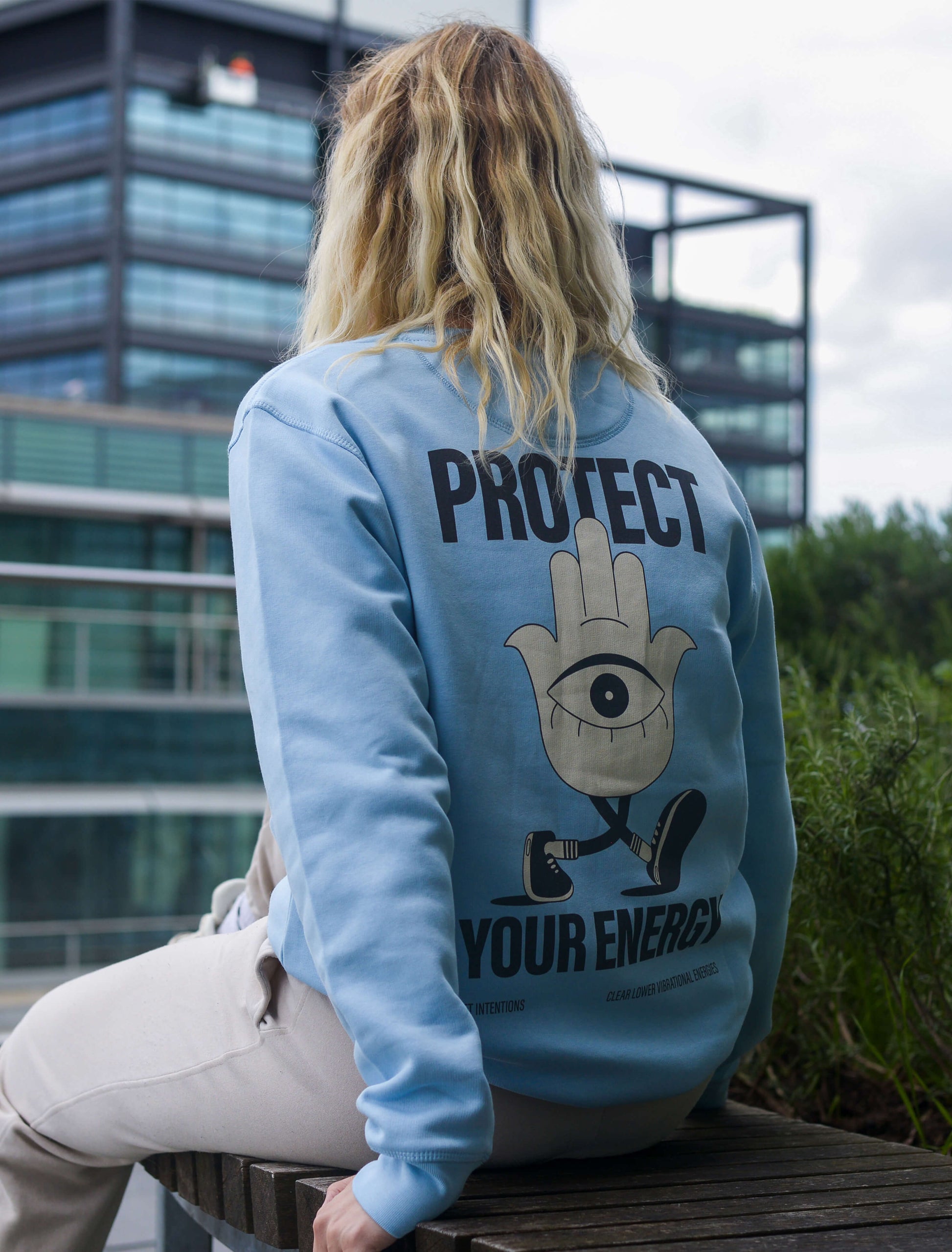 Protect your energy hamsa hand sweater in baby blue. Blonde model wearing positive streetwear