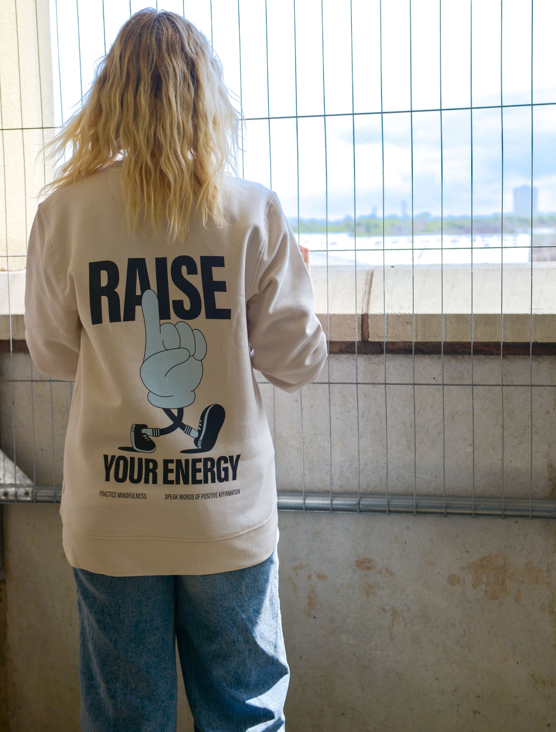Blonde woman wearing raise your energy sweater. positive affirmation and mindfulness inspired design jumper clothing, trendy